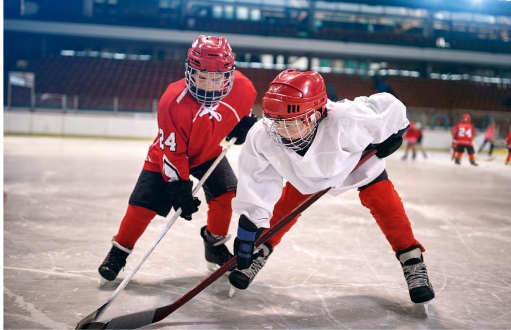 Two young kids learning to play ice hockey