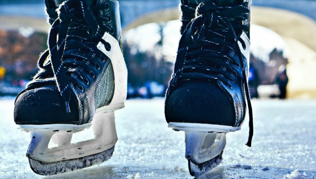 A close up of ice hockey skates on the ice.